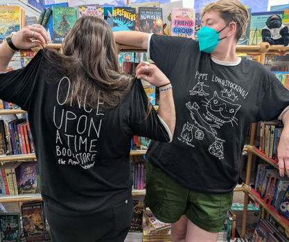 Apollo showing off the back of the Pippi Bookstore Shirt and Iz showing off the front of the Pippi Bookstore Shirt.